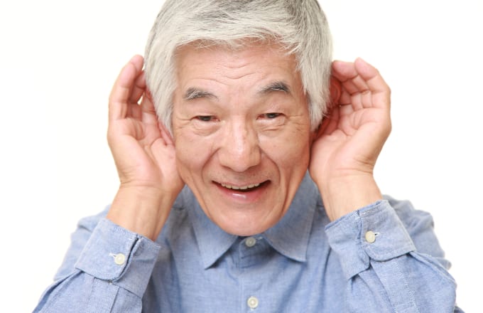 An old man cupping both his ears