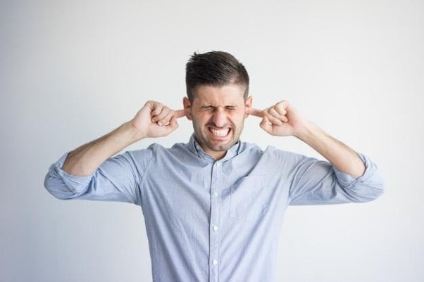 a man covering his ear with his fingers