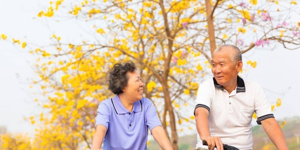 happy asian senior couple ride on bicycle  in the park